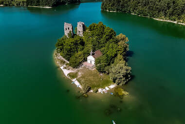 eine insel in mitten des see, die insel hat eine burgruine und es ist ein drohnenfoto ; fotografiert von fotoboss.ch